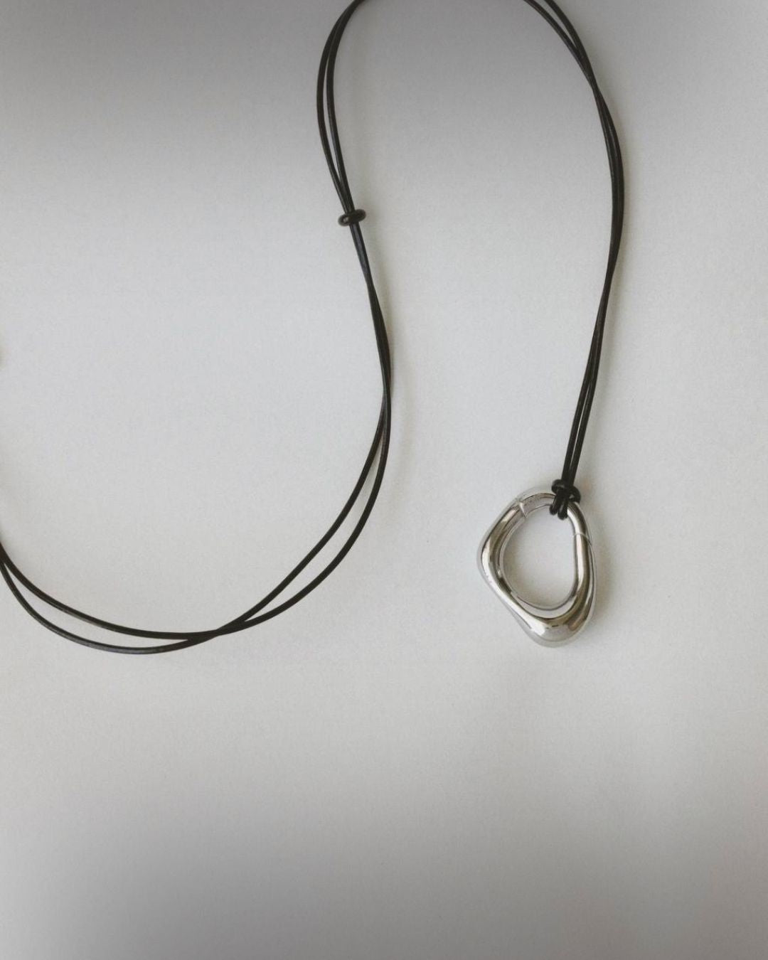 Momentum Necklace by Enso Design Lab, showing the pendant and leather cord. The design combines innovative steel with a minimalist aesthetic.
