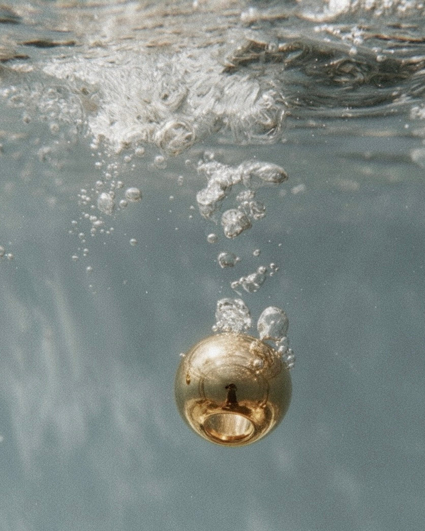 Gold ring submerged in water with bubbles around it