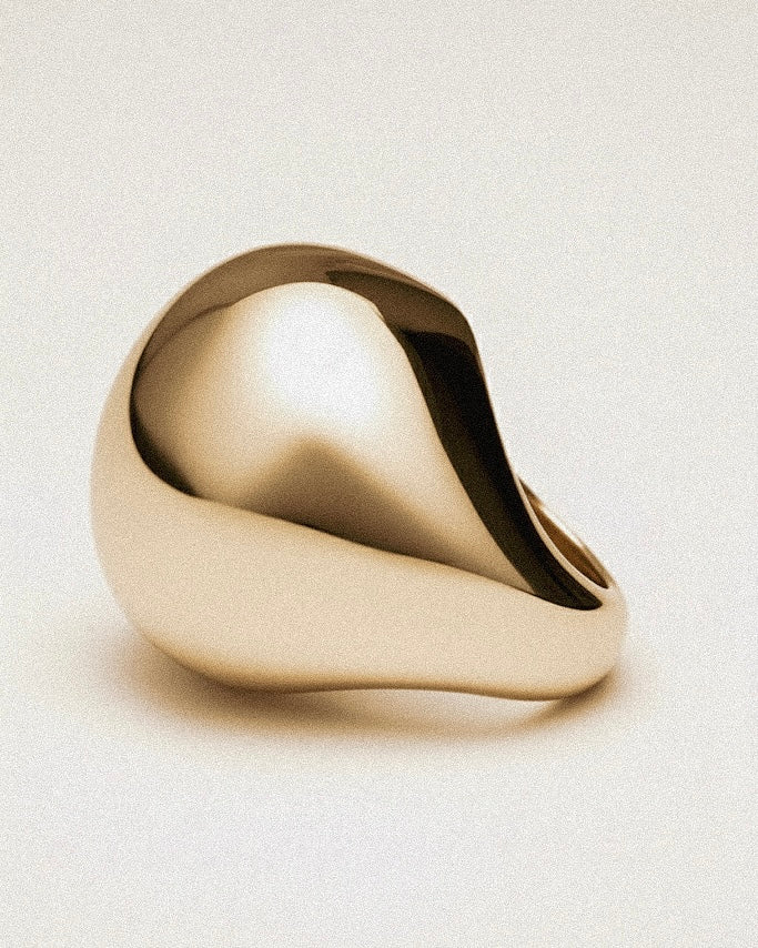 Gold ring with a modern design on a light beige background