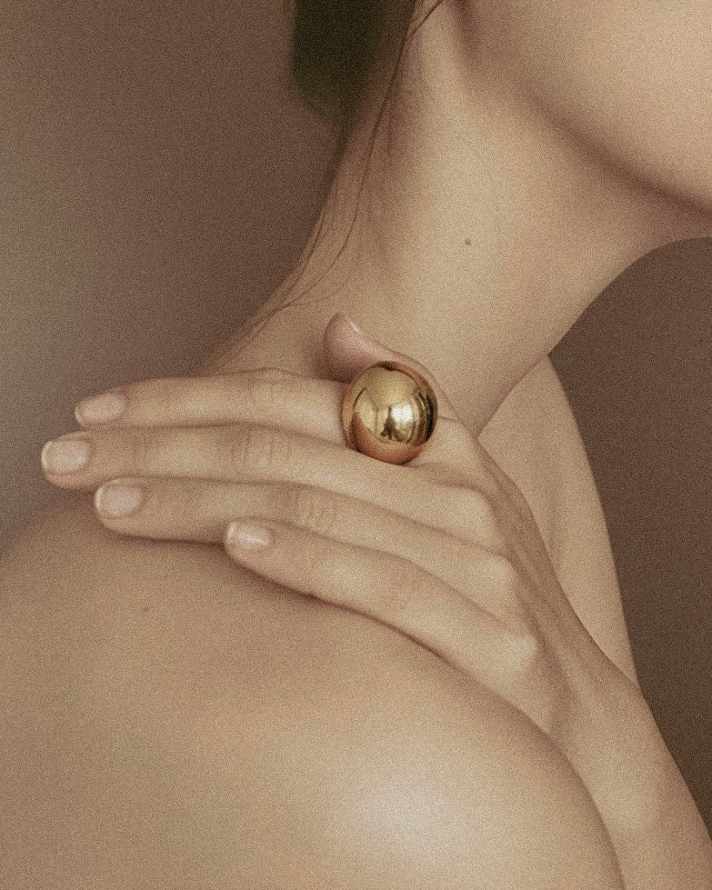 Gold ring on a hand against a neutral background