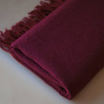 Close-up of a premium cashmere scarf in burgundy, showcasing its fine texture and hand-finished fringes by Enso Design Lab™.