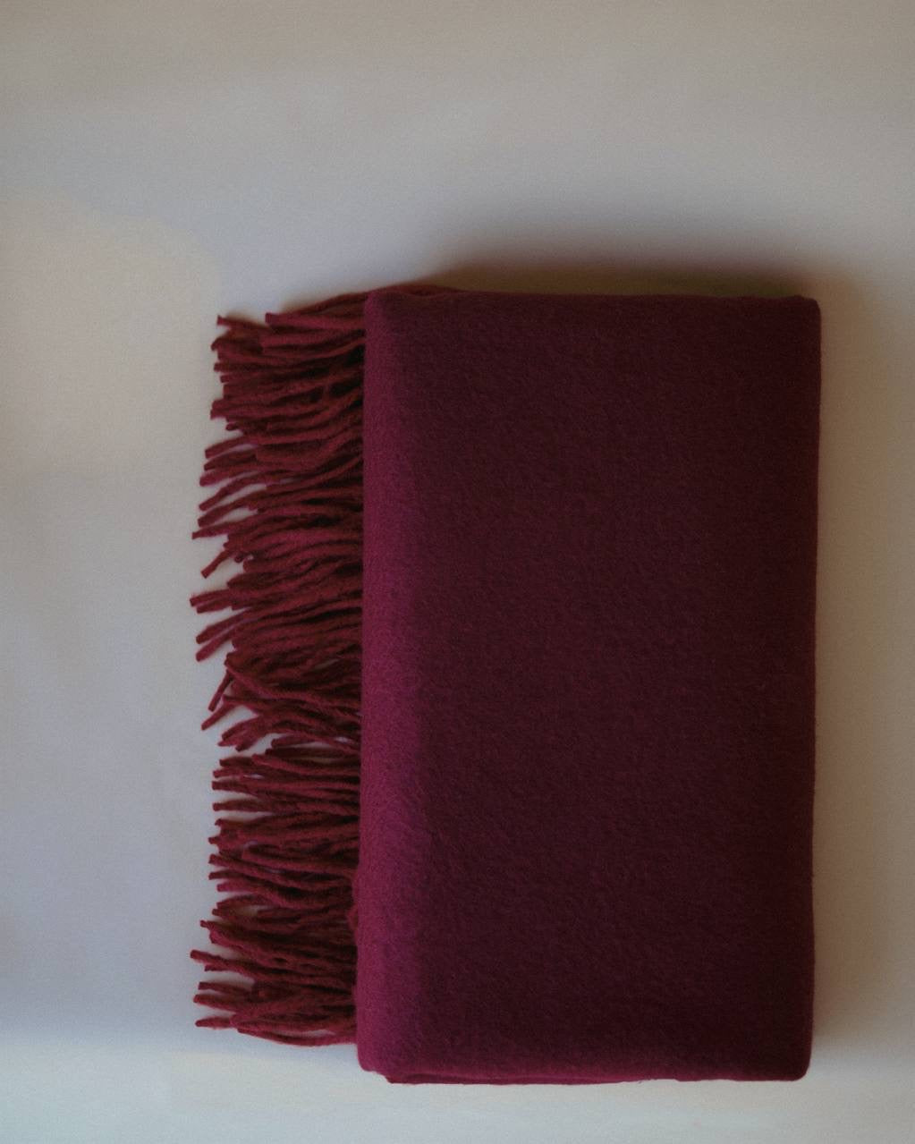 Side view of a burgundy cashmere scarf, reflecting minimalist luxury and sophisticated craftsmanship guided by Ani Han.