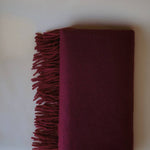 Side view of a burgundy cashmere scarf, reflecting minimalist luxury and sophisticated craftsmanship guided by Ani Han.