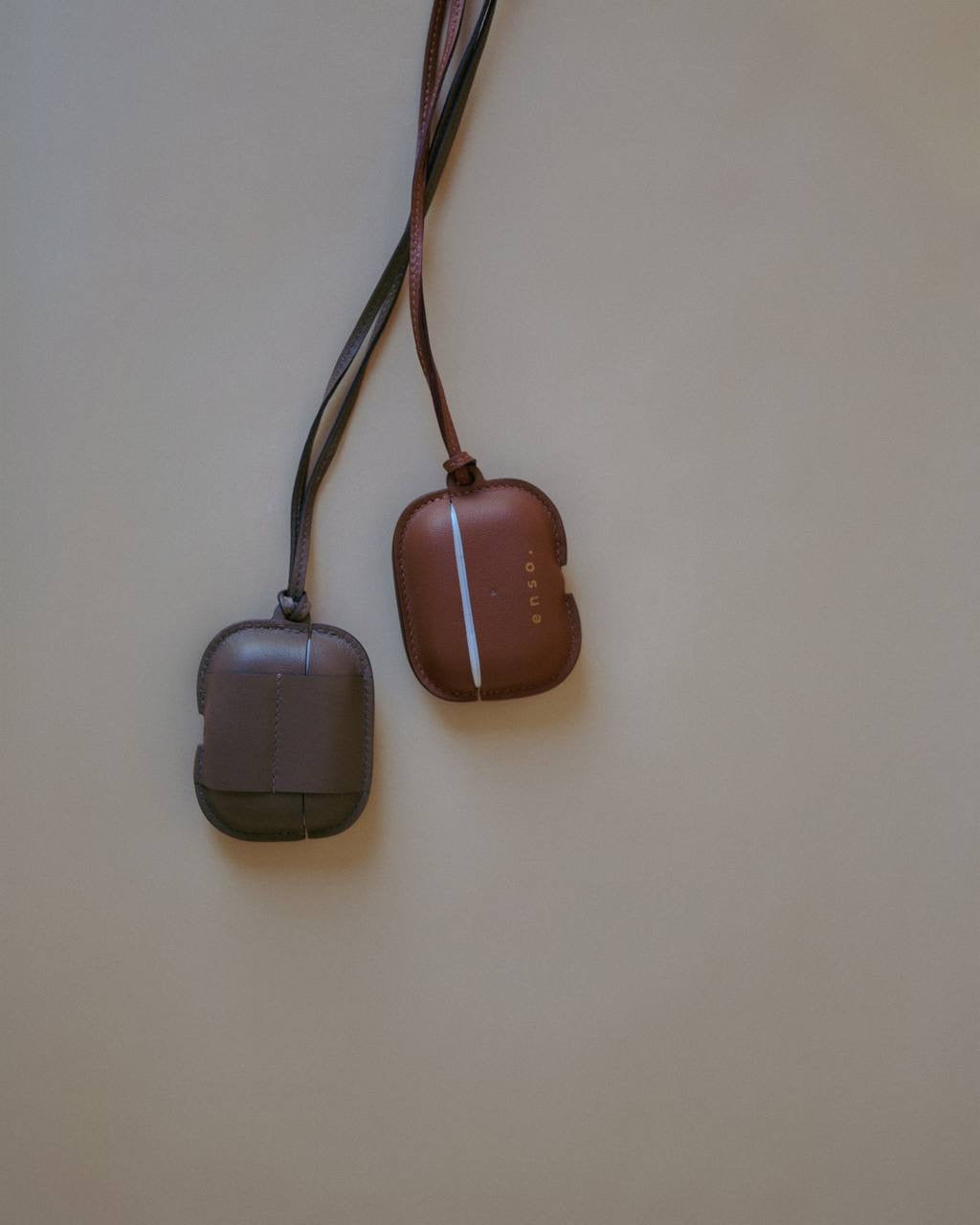 A comparison of two Leather AirPods Case Necklaces in Slate Mirage and complementary shades, reflecting Enso Design Lab™’s philosophy of understated elegance.