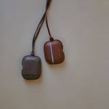 A comparison of two Leather AirPods Case Necklaces in Slate Mirage and complementary shades, reflecting Enso Design Lab™’s philosophy of understated elegance.