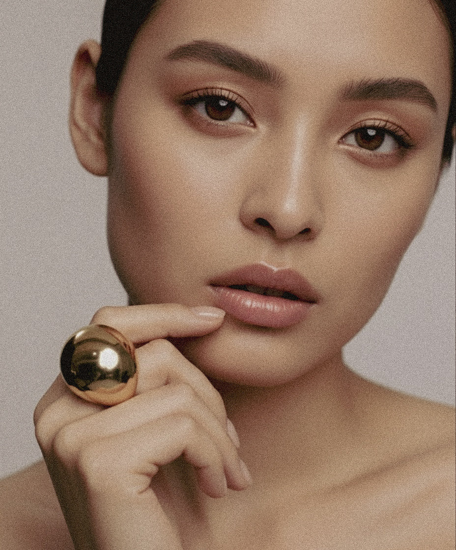 Model wearing gold-plated Flow Ring sculptural brass jewelry by Enso Design Lab, showcasing mirror-polished finish
