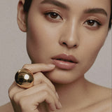Model wearing gold-plated Flow Ring sculptural brass jewelry by Enso Design Lab, showcasing mirror-polished finish