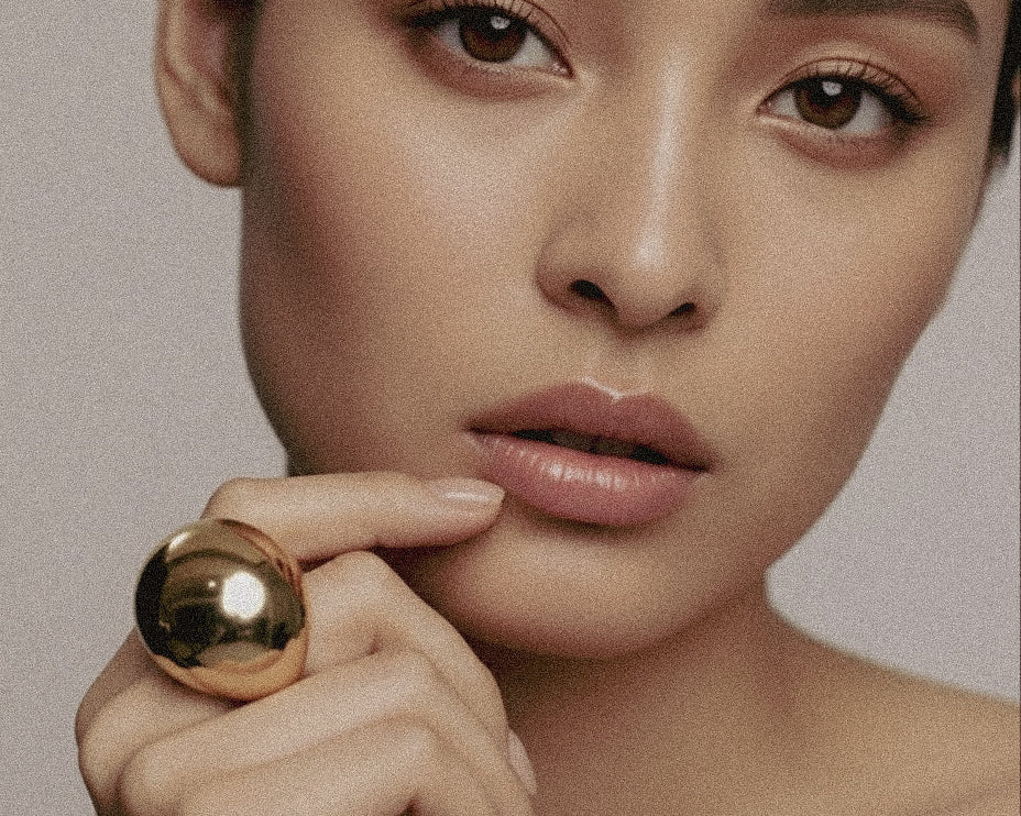 Model wearing gold-plated Flow Ring sculptural brass jewelry by Enso Design Lab, showcasing mirror-polished finish