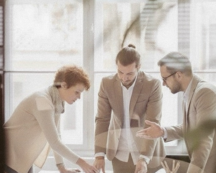 Three people in a professional setting, possibly a meeting or discussion.