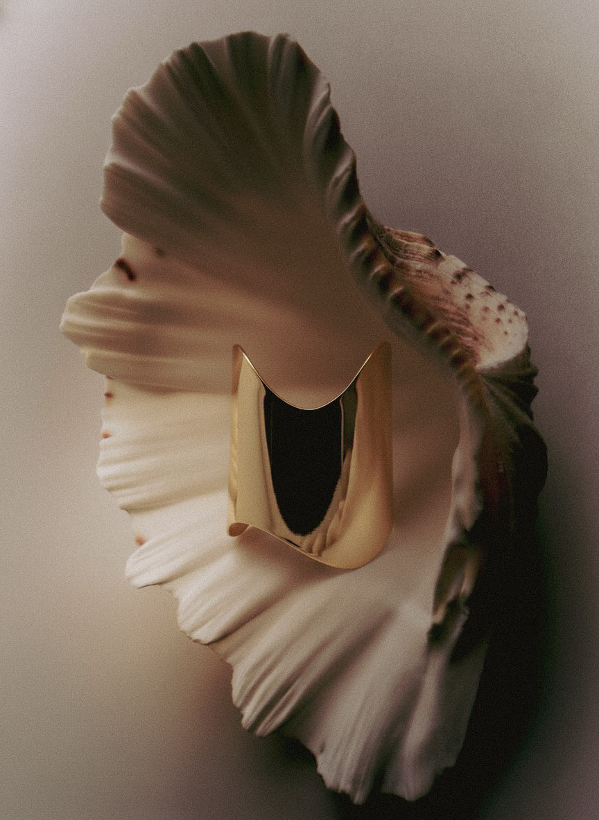 Close-up of Shell Cuff bracelet showing mirror-polished gold finish and organic form