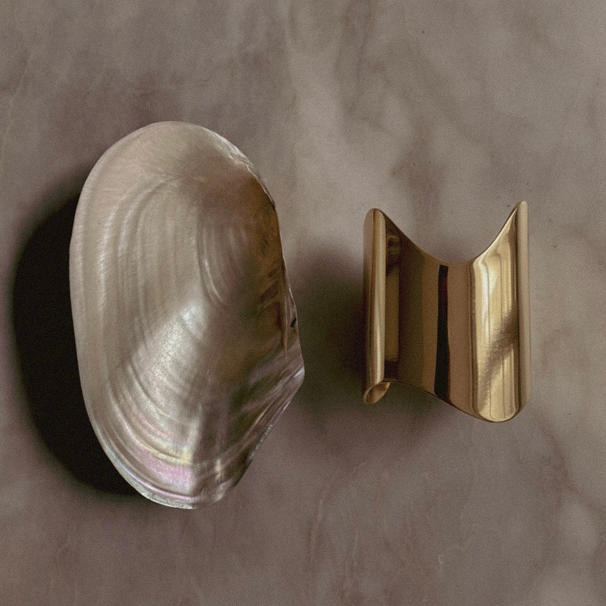 Clam shell and Shell Cuff gold-plated bracelet on a gray background