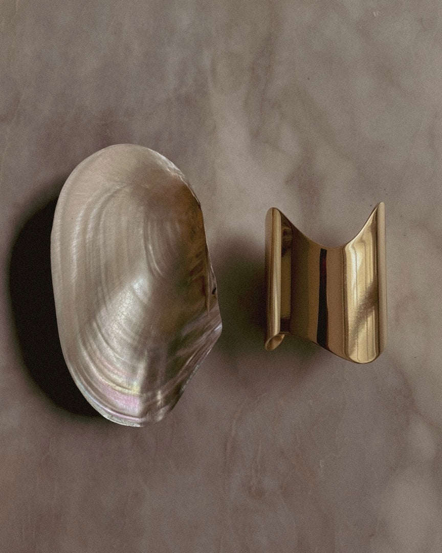 Clam shell and Shell Cuff gold-plated bracelet on a gray background