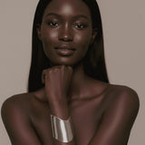 Model with long, straight hair wearing a silver Shell Cuff on a beige background.