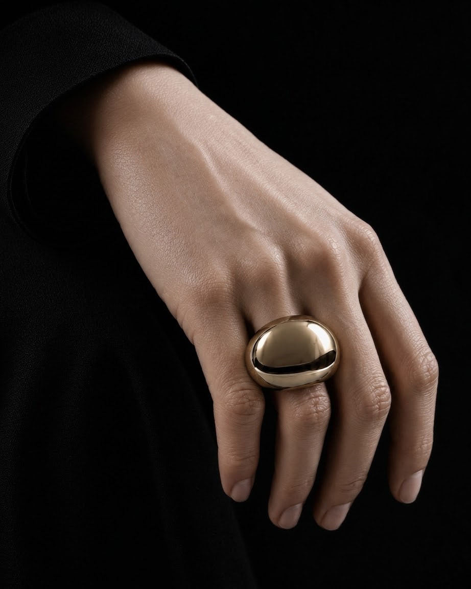 CONTAIN ring in champagne mirror finish worn on a hand with a black tailored sleeve