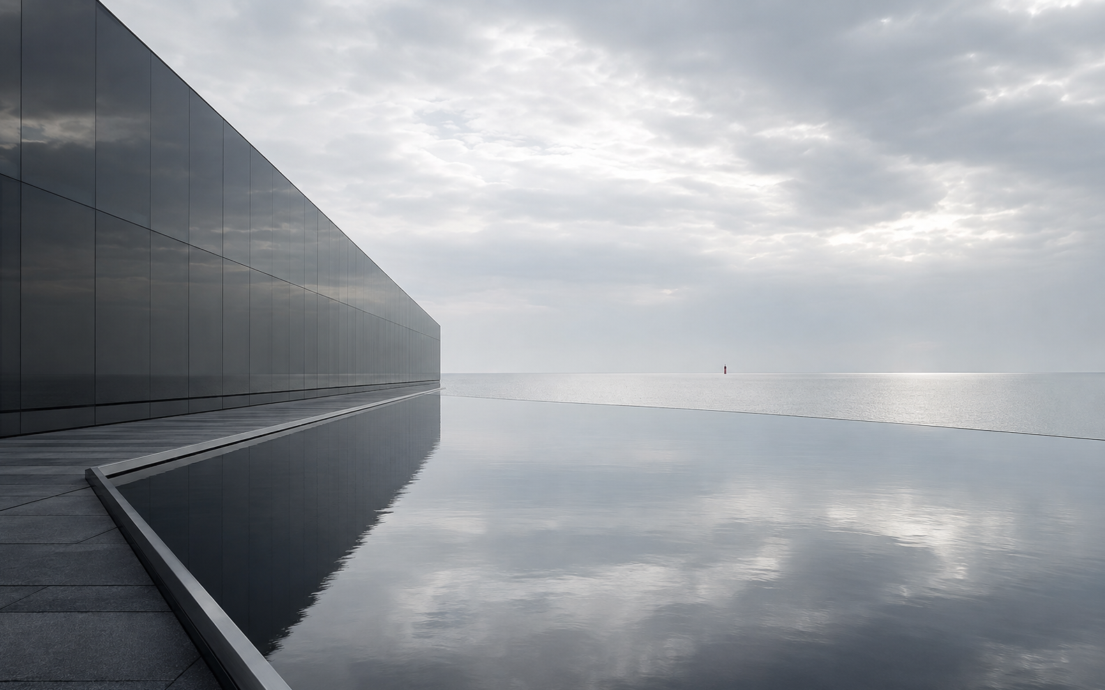 Minimal black glass architecture meeting a silver sea horizon